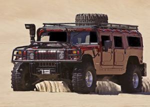 Hummer SUV driving off road on sand dunes